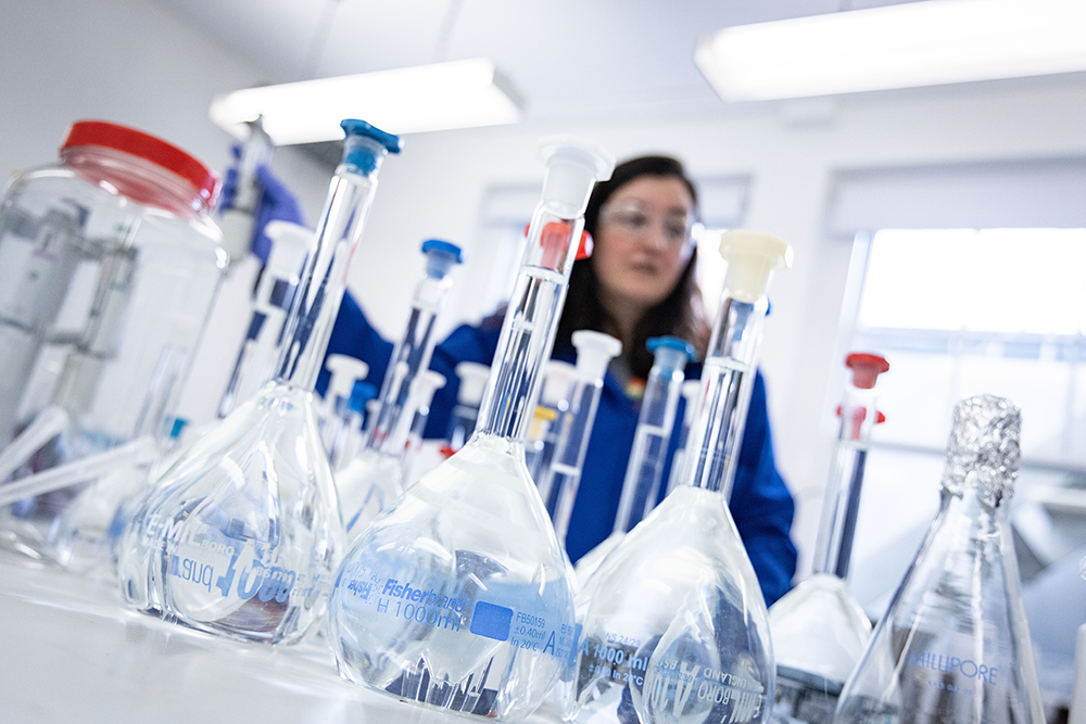 A collection of test tubes sits on a desk in front of a scientist.